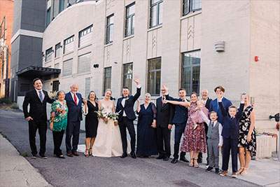 Newlyweds pose with their families in front of the hotel