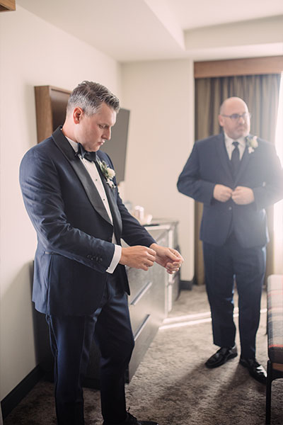 Rob gets ready for the wedding with friends in a guestroom